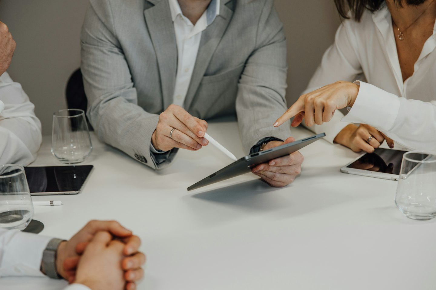Para profesional bisnis berkolaborasi menggunakan tablet di atas meja putih.